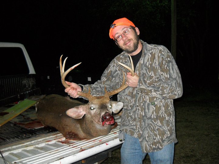 a man standing next to a dead deer