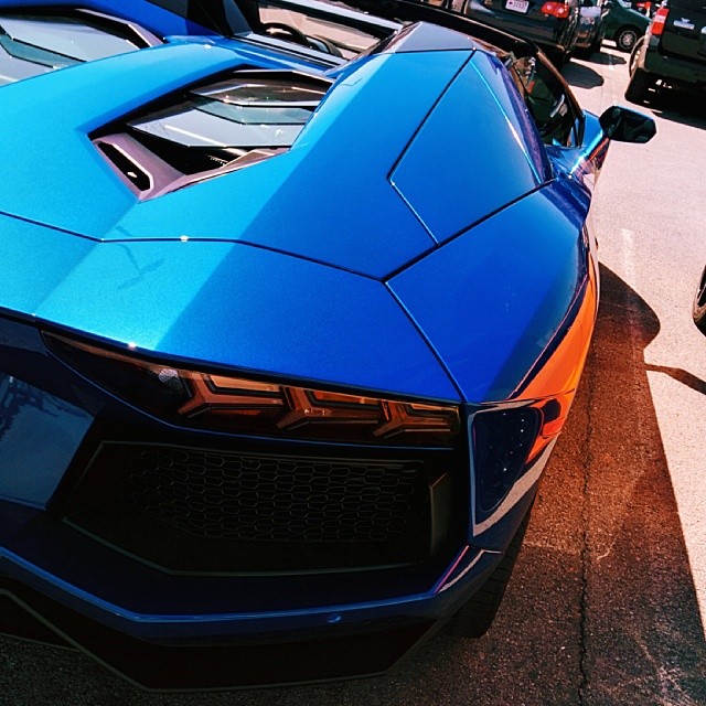 two men stand next to the shiny blue sports car