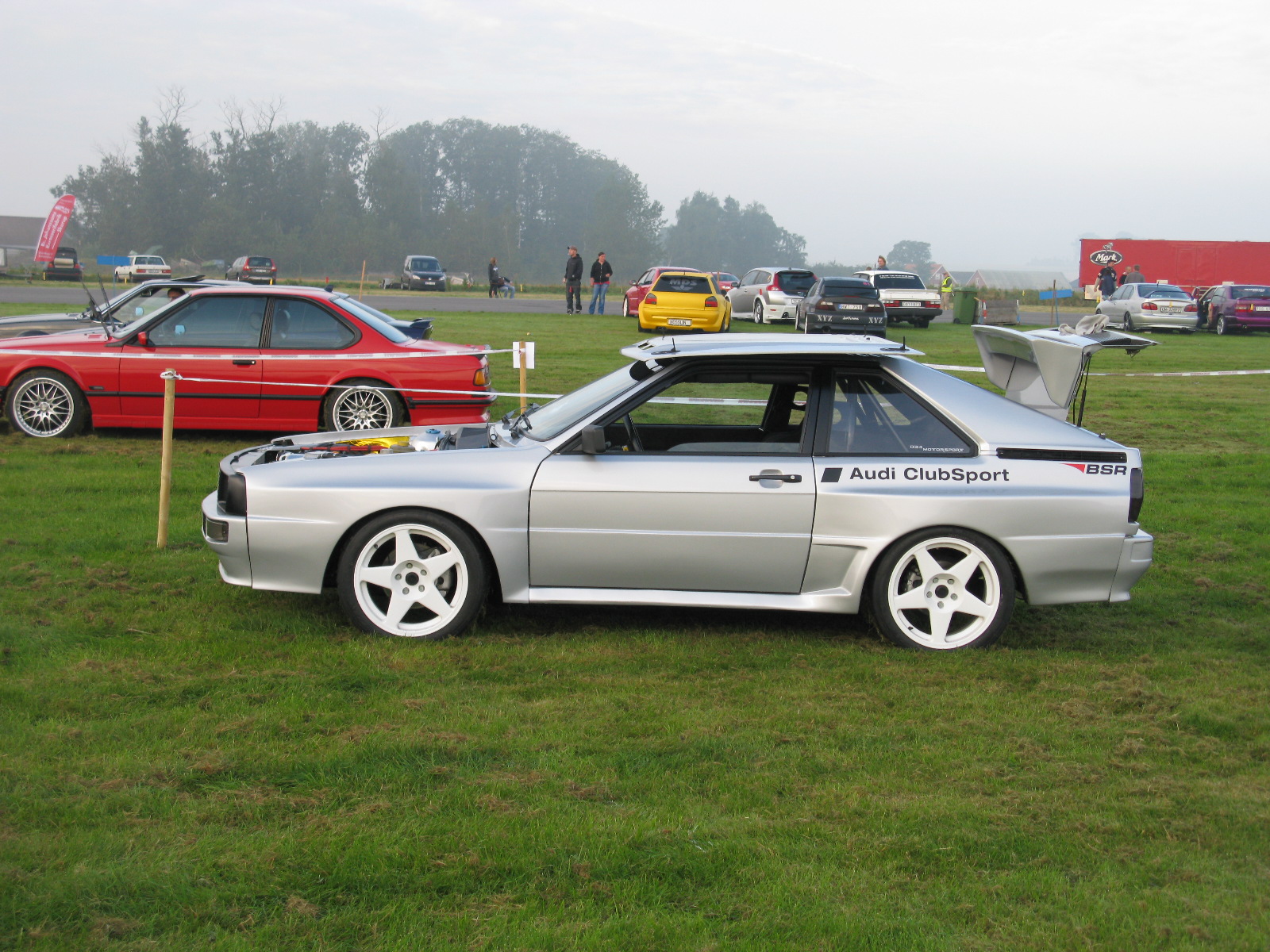 a silver car parked in a field at an auto show