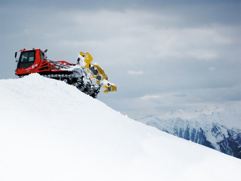 an orange truck and a snowboarder going up the snowy hill