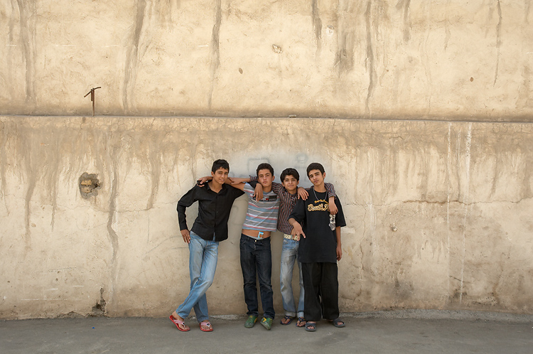 four boys standing against a concrete wall