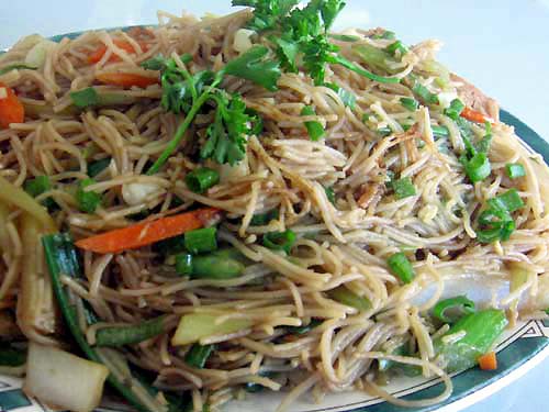 a plate full of noodles, carrots and veggies