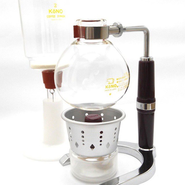 a glass and wood stove top kettle with a strainer and measuring cup