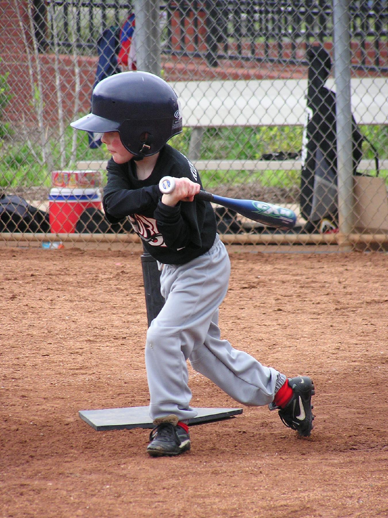 a young child holding a baseball bat on top of a field