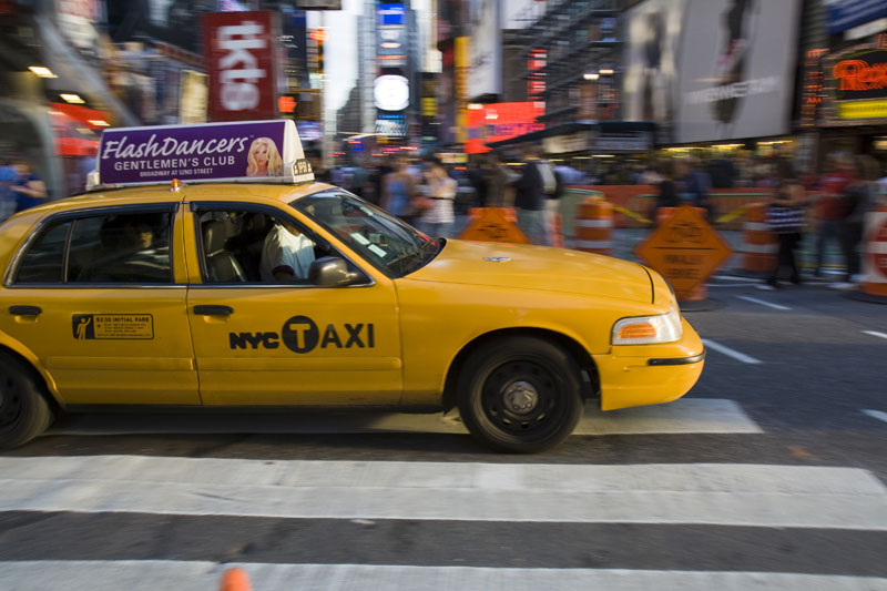 a taxi driving down the street with people on it