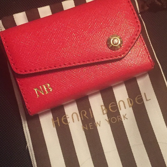 an empty red wallet is laying on a striped pillow