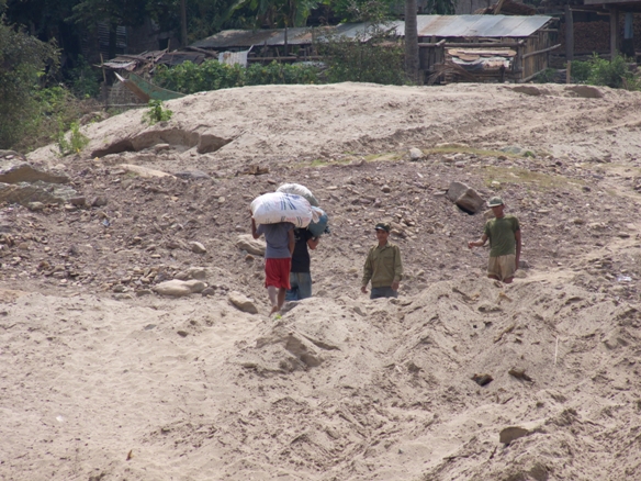 people carrying goods standing on dirt and sand