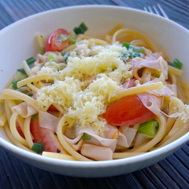 a bowl of linguini with meat, cheese and tomatoes