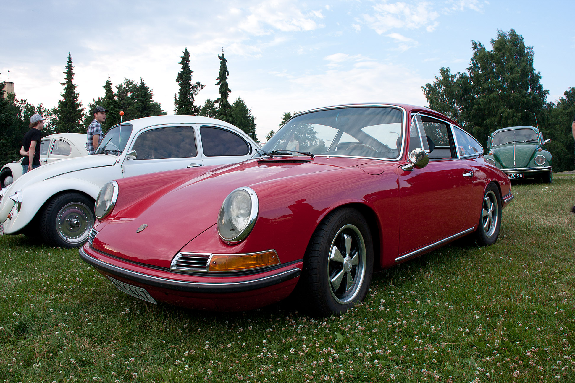 two old porsches parked next to each other on grass