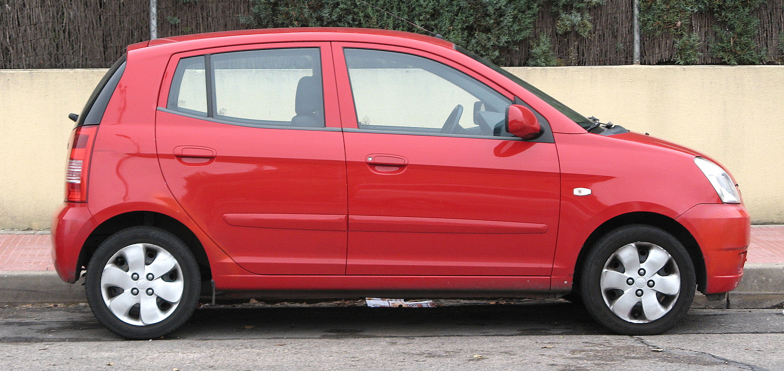 a small red hatchback car is parked by itself