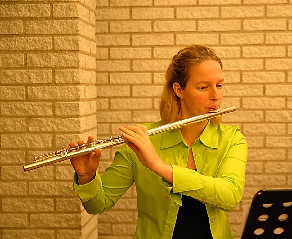 a woman in a yellow top is playing a silver musical instrument