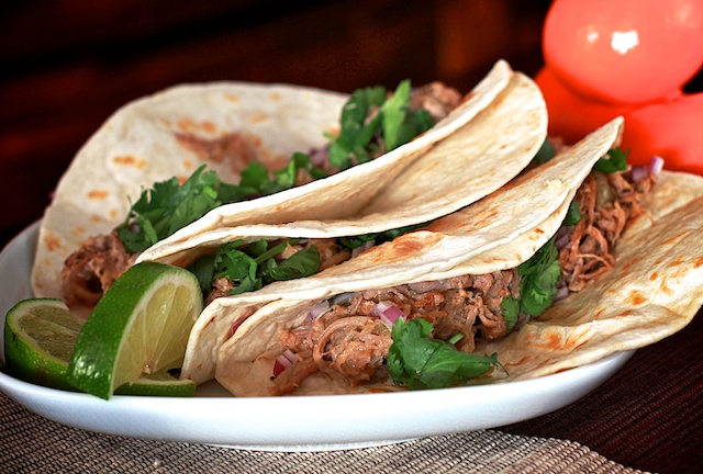 shredded meat tacos on a plate with lime and cilantro