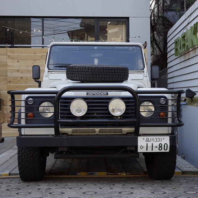 a black and white truck with white tires and a wooden building in the background