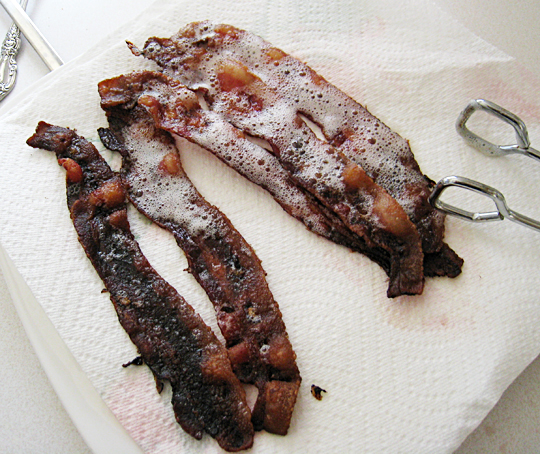 pieces of bacon that have been cooked are sitting on a white napkin