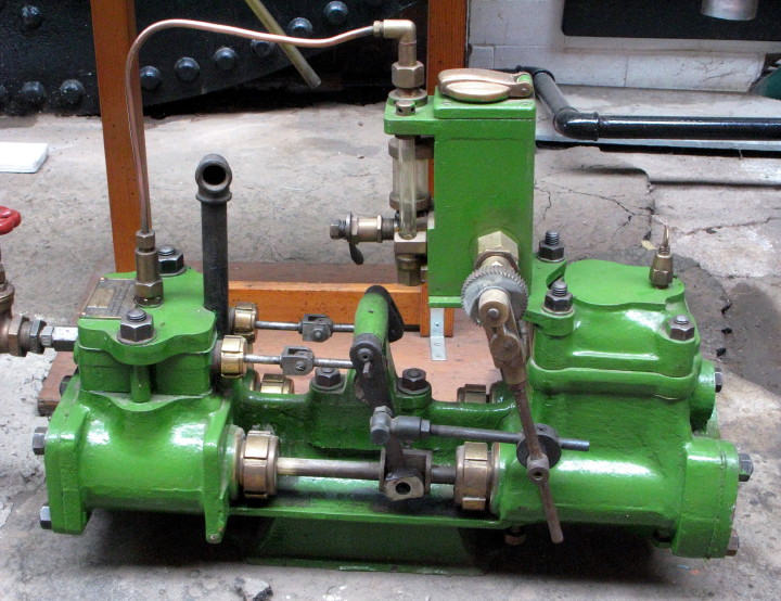 green and yellow engine on concrete next to pipes