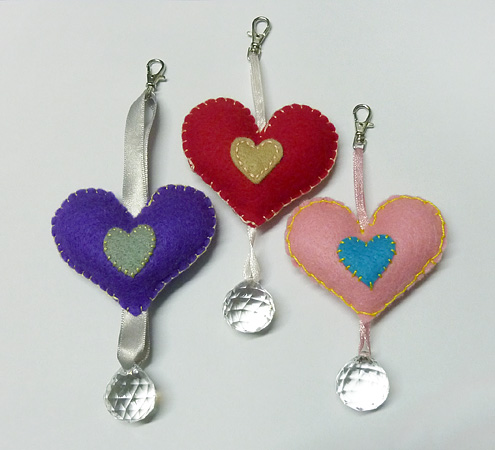 three heart shaped ornaments are hanging on a table