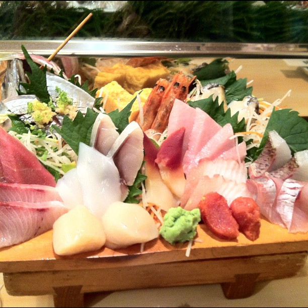 assorted seafood on a wooden platter next to a glass