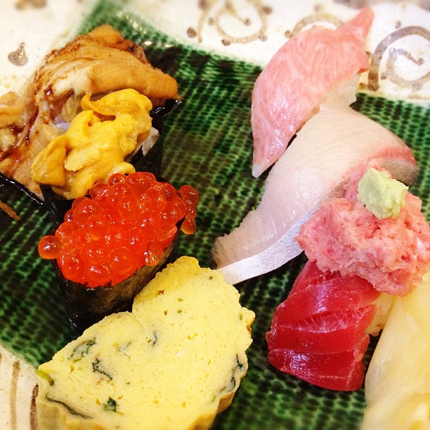 various types of sushi displayed on a green plate