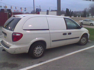 a white minivan sits in the middle of a parking lot