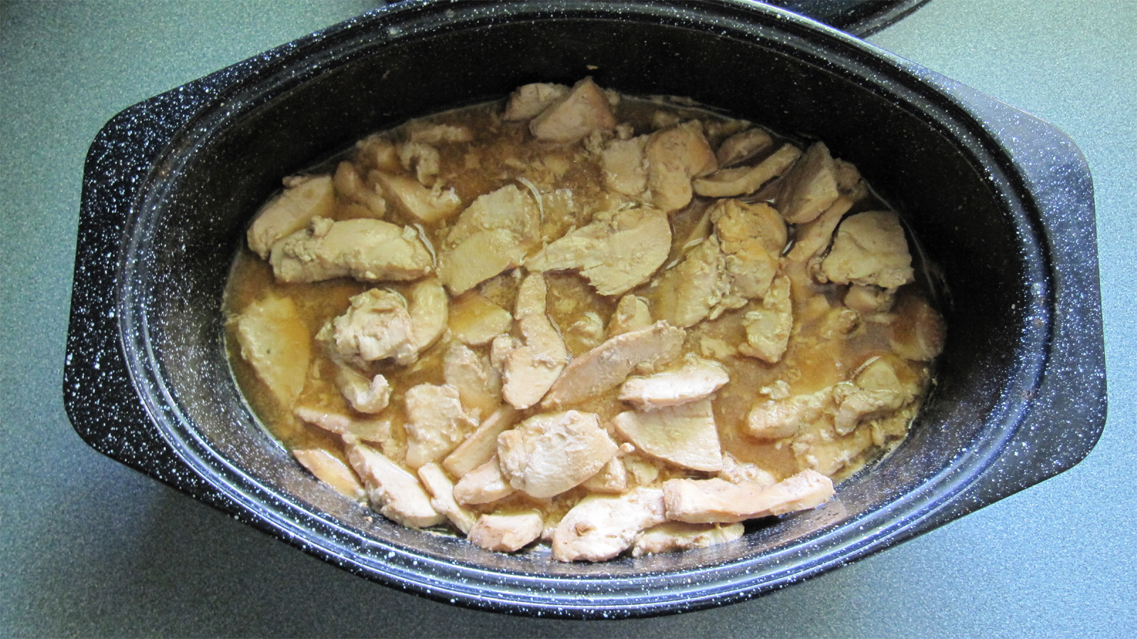 cooked chicken with brown sauce in black pot