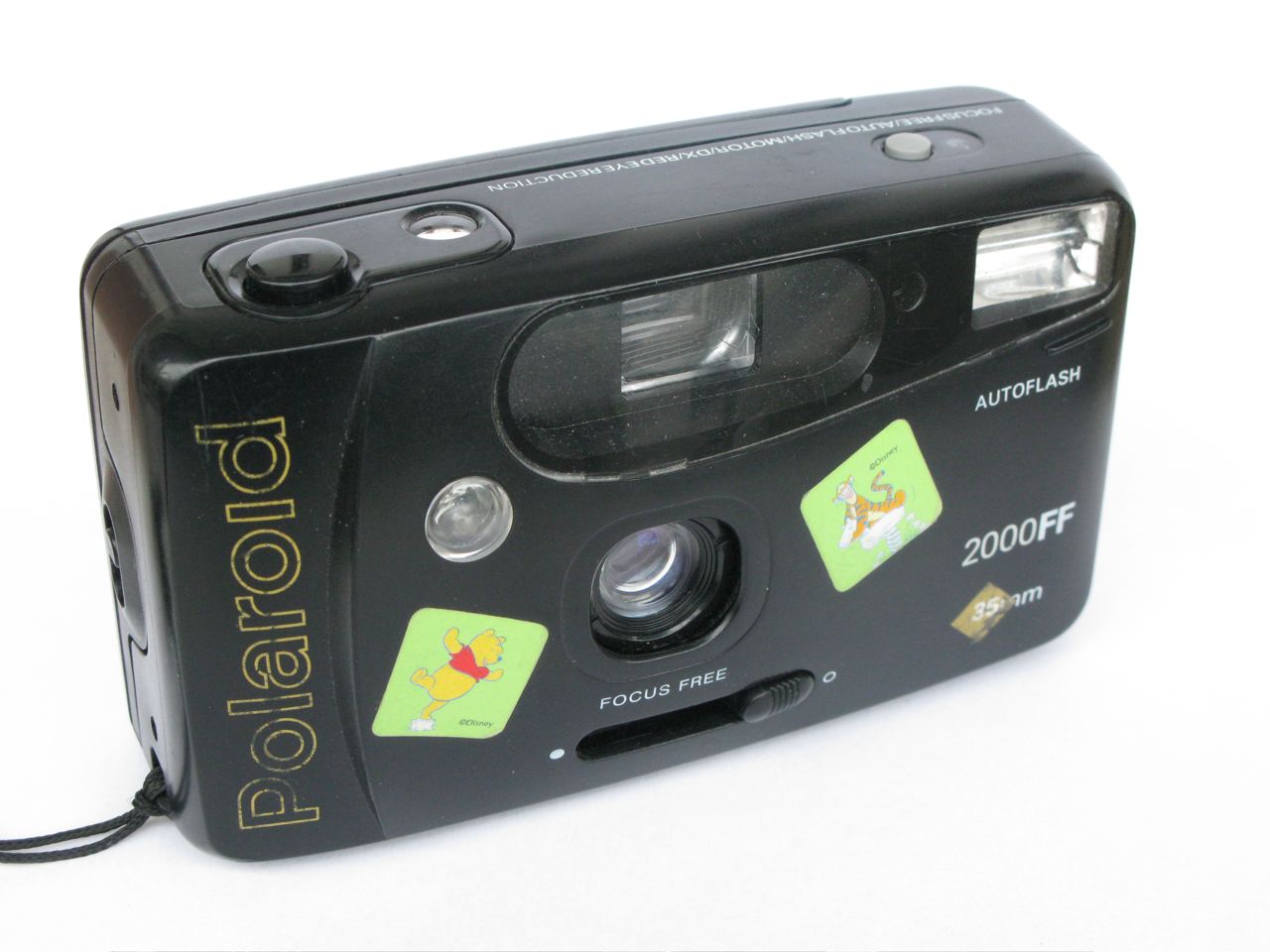 a black digital camera on white surface with yellow stickers on the body