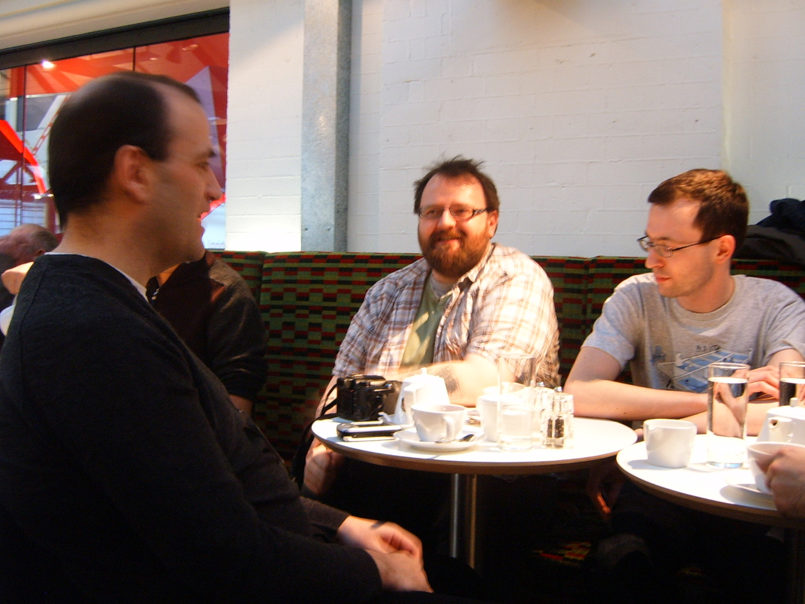 three men sitting at a table with cups and drinks