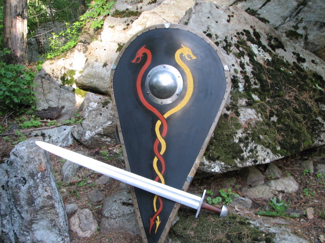 an unusual sword and shield stand beside a boulder wall