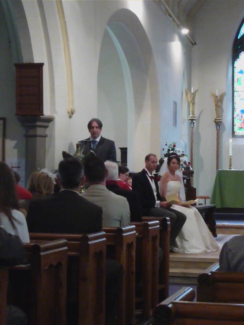people sit in pews of a church, one bride wearing a veil