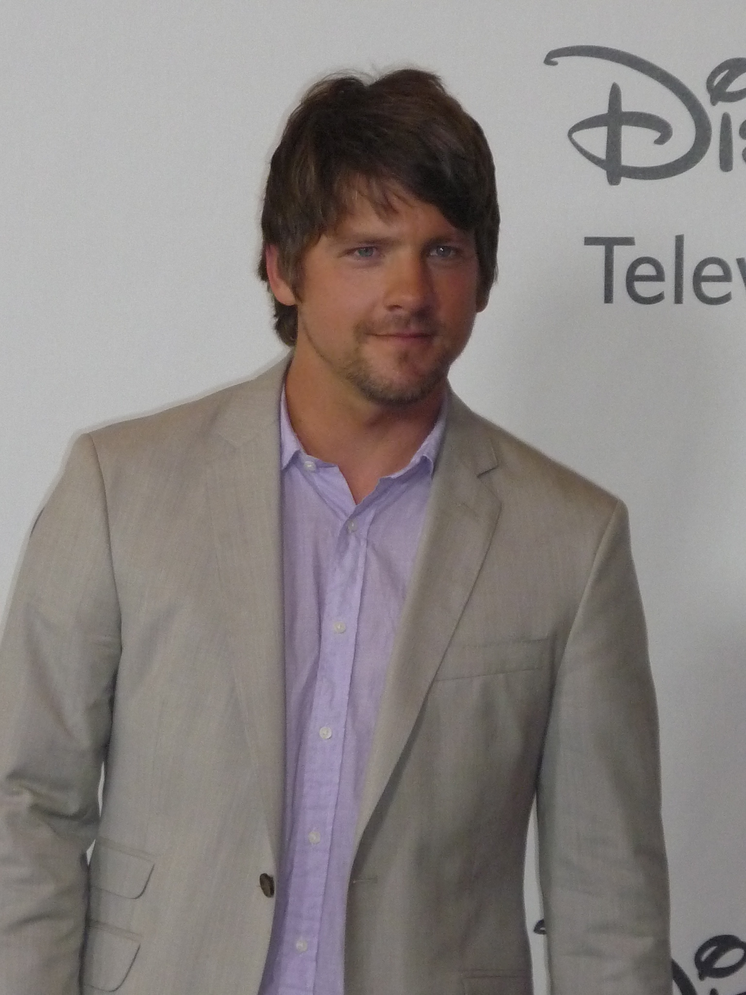 a male in a light blue shirt and blazer posing for the camera