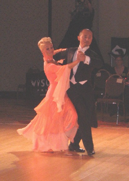 a man and woman in formal attire doing a dance