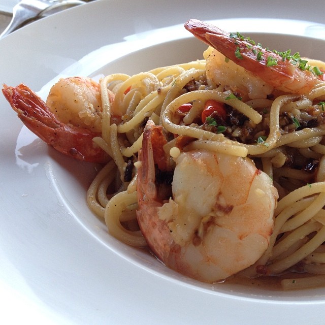 a plate of pasta with shrimp, herbs and sauce