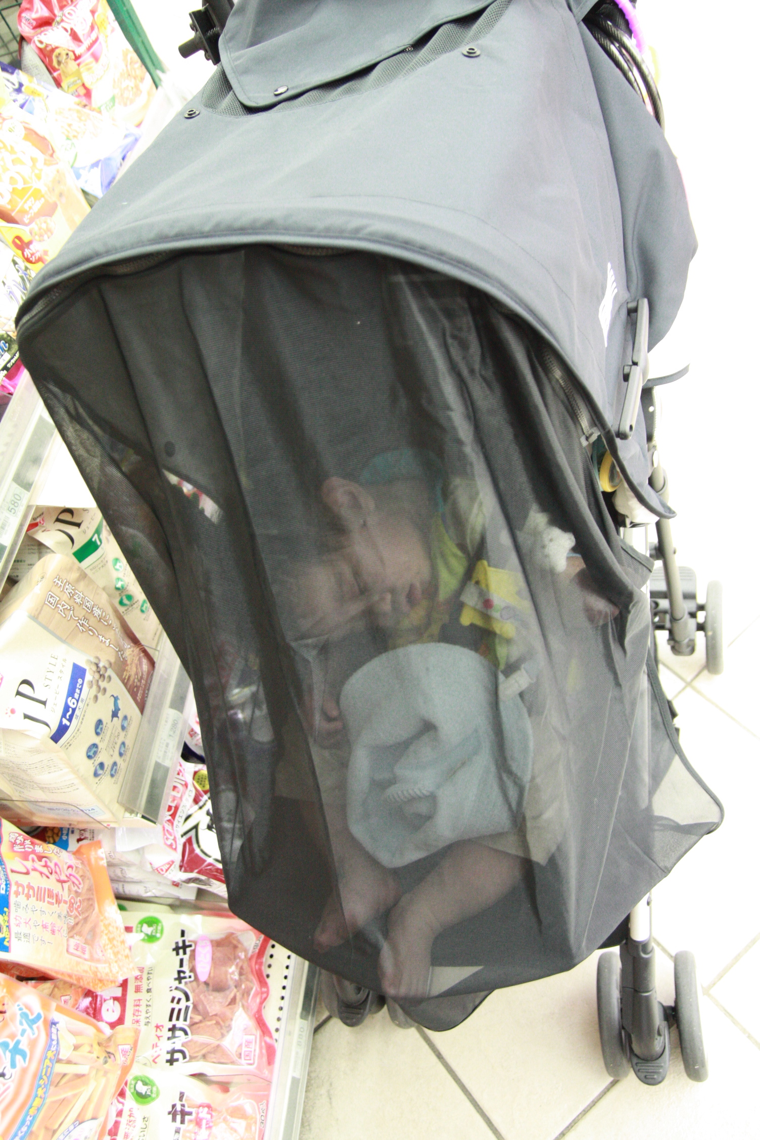 an infant in a stroller with snacks on the ground