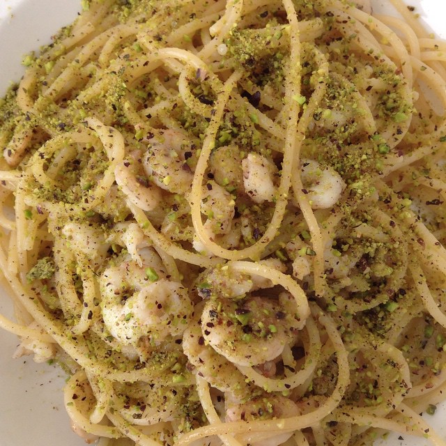 a bowl of pasta with shrimp and pesto on it