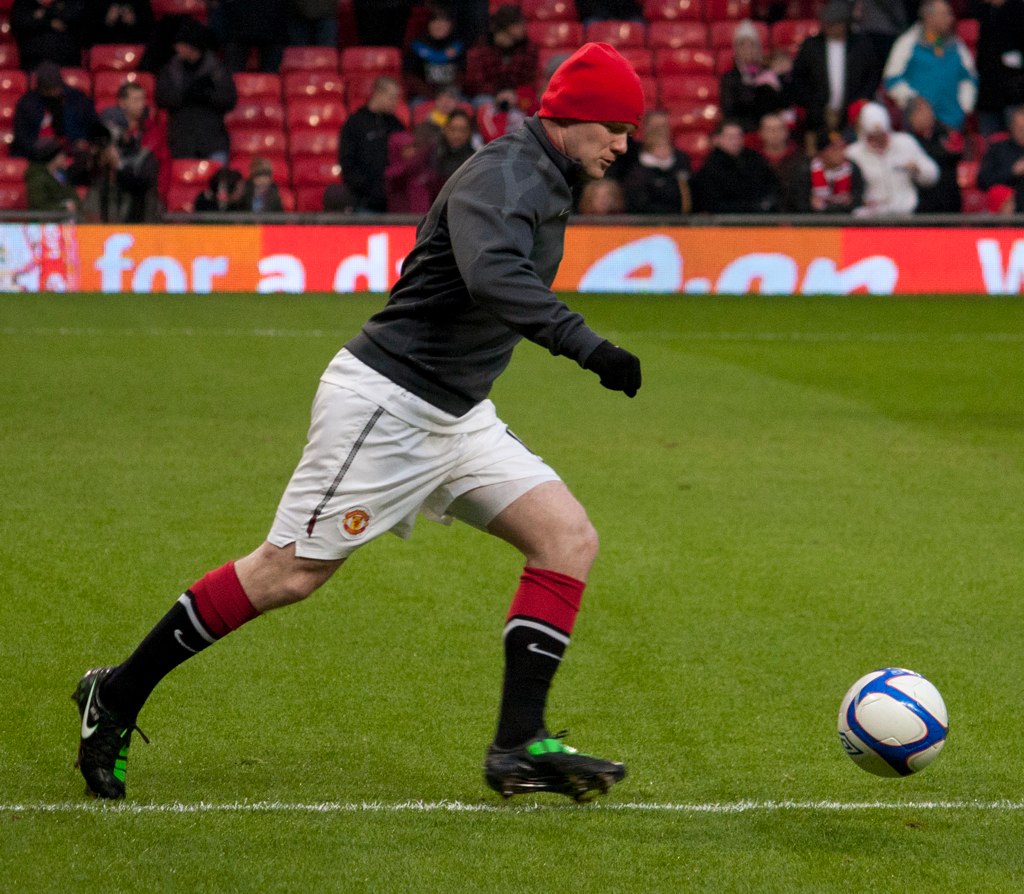 a man playing soccer wearing short shorts, a red hat and black boots