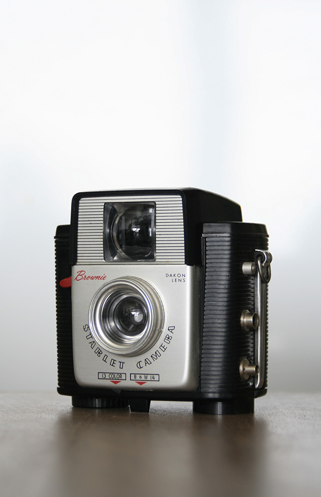 a vintage camera on a wooden surface that is very small