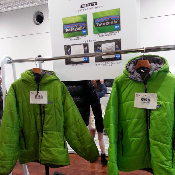 two jackets hanging on clothes racks while two people are looking