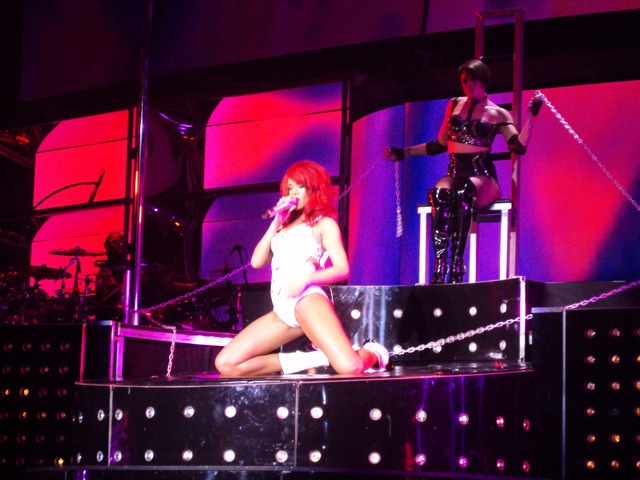 a woman with red hair and boots in front of microphone on stage