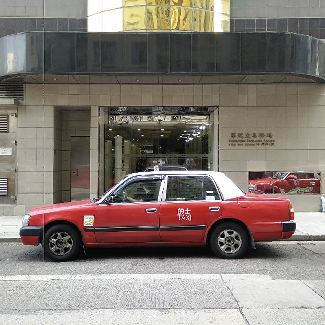 a red cab is parked in front of a building