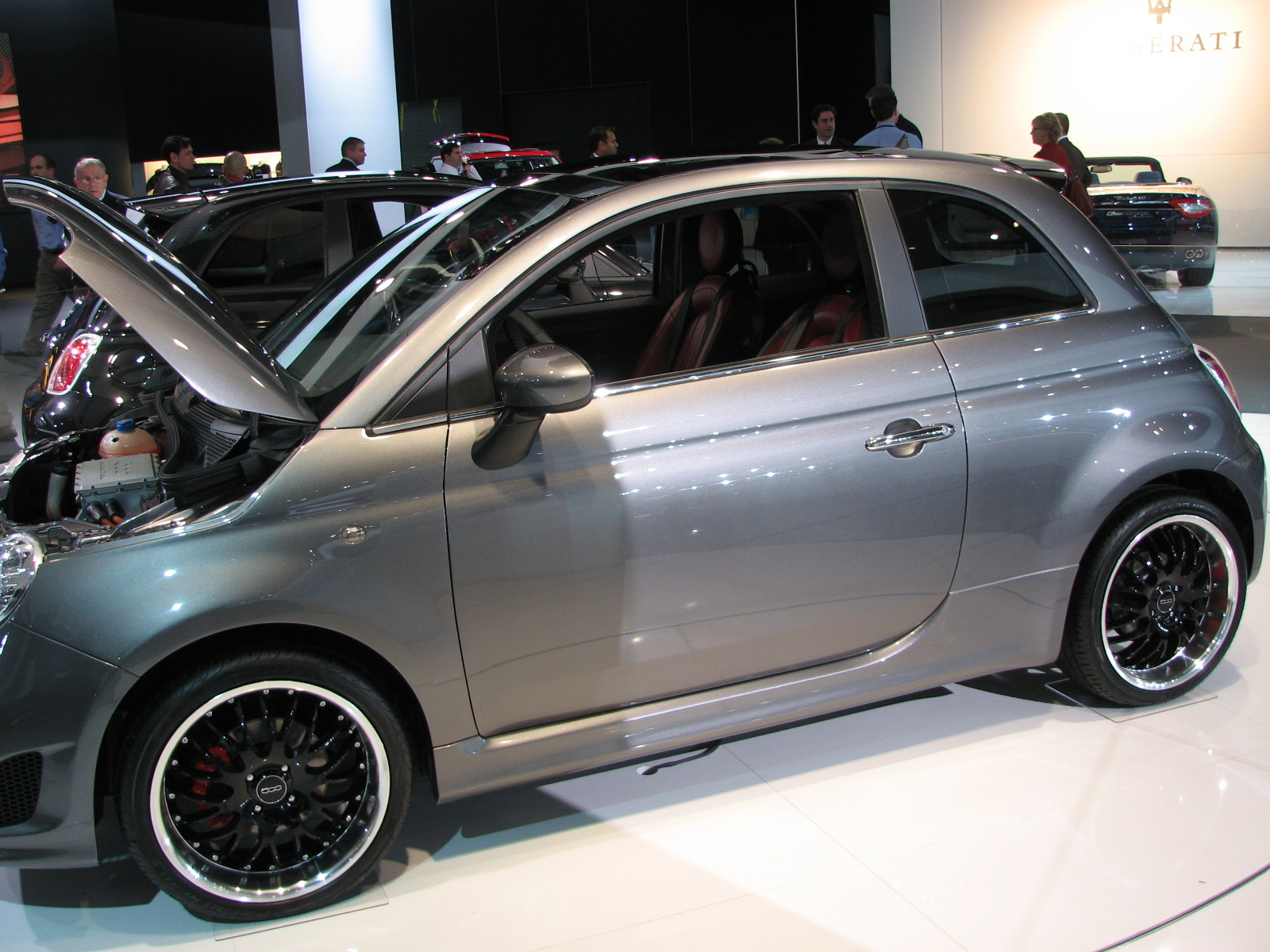 a smart car with its open hood and wheels on display