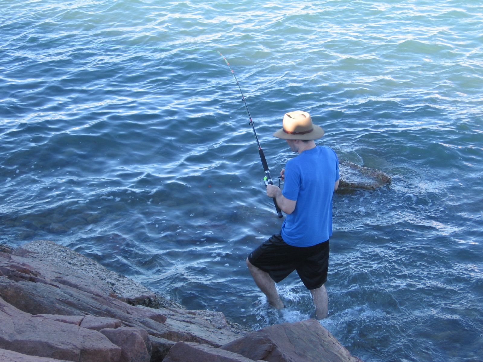 a man is standing at the edge of the water while fishing