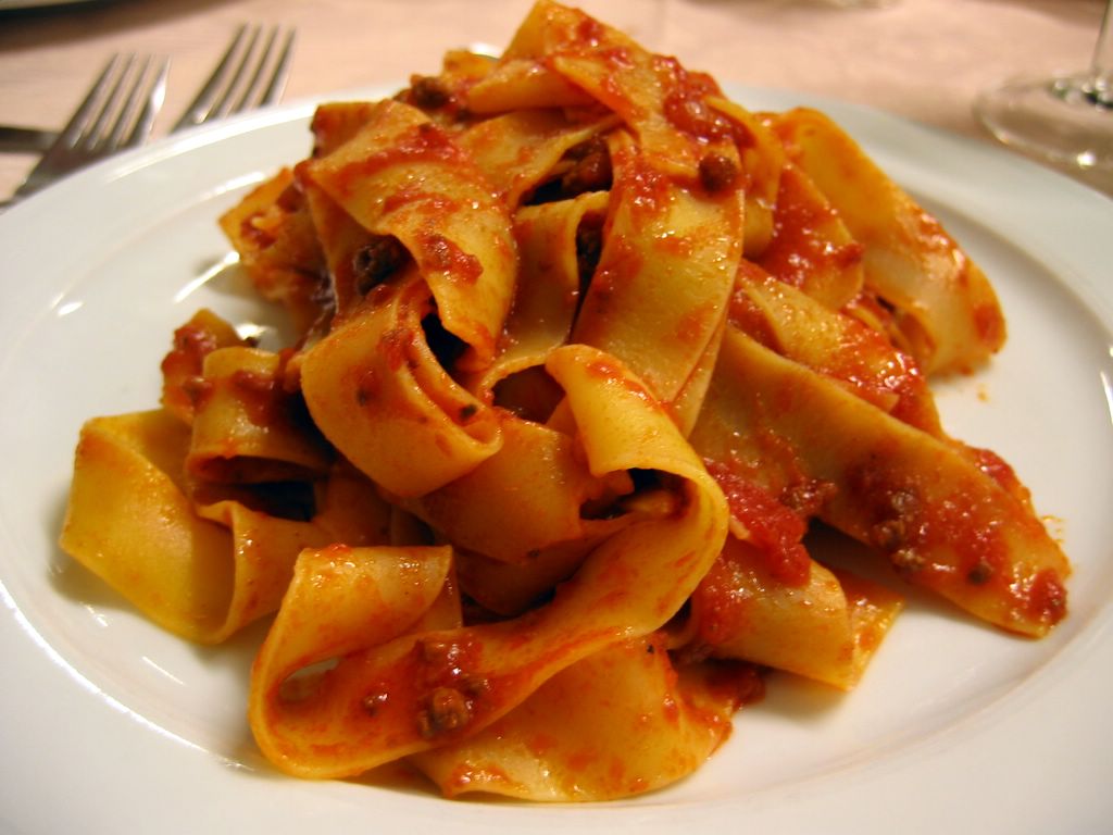pasta with sauce on white plate with utensils