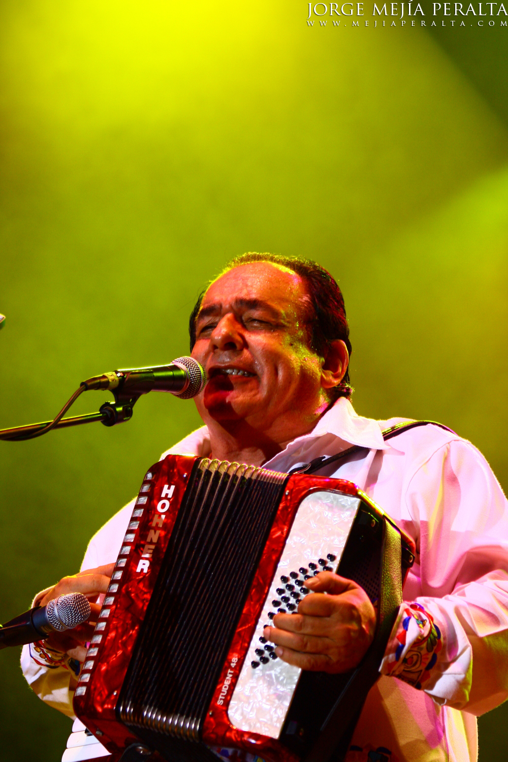 a man holding a large accordion while standing in front of a microphone