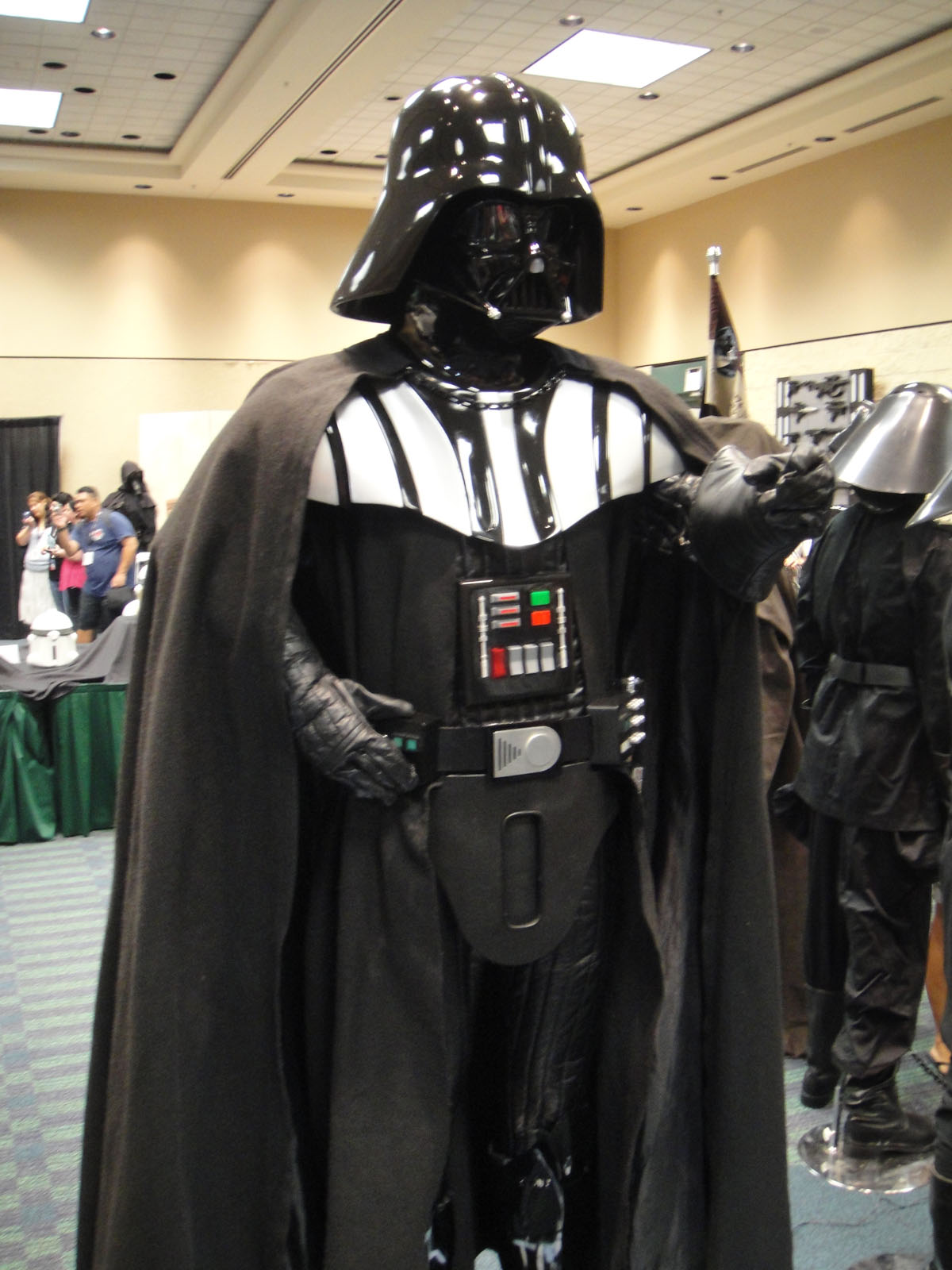 a darth vader costume is displayed with people looking on