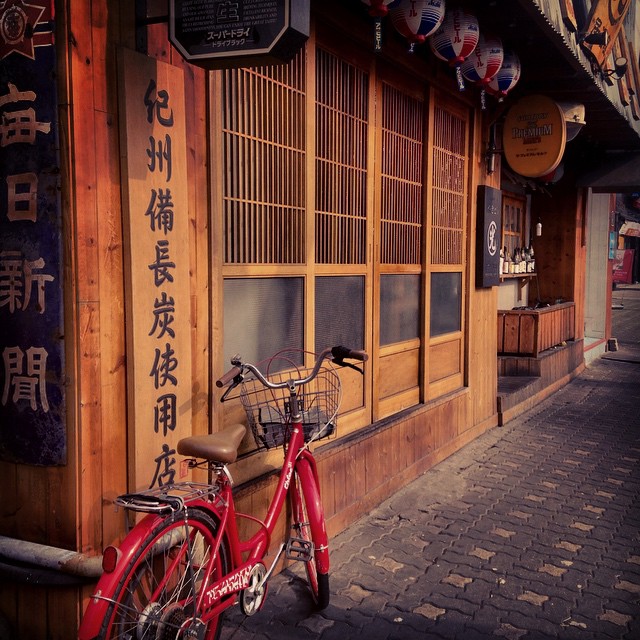 a red bicycle is leaning against the wooden building