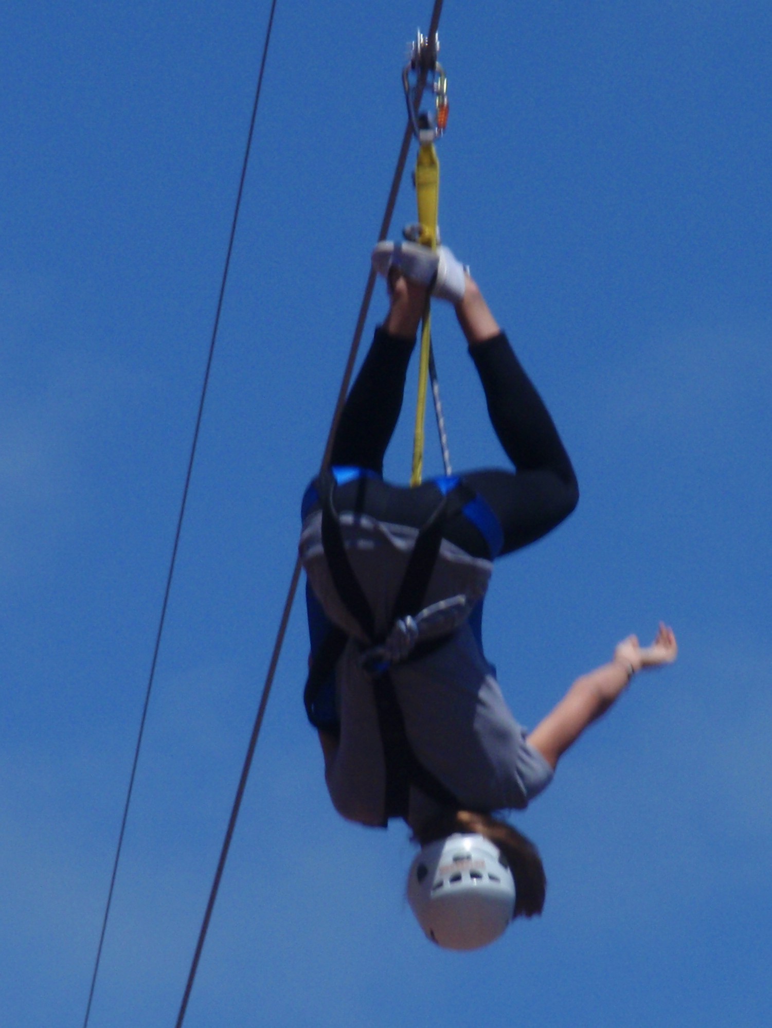 a man hanging upside down from the side of a zip line