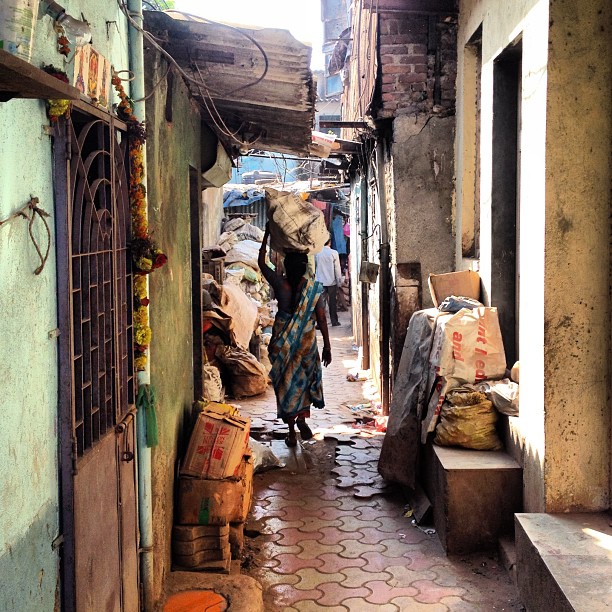 woman walking down a alley lined with furniture and junk