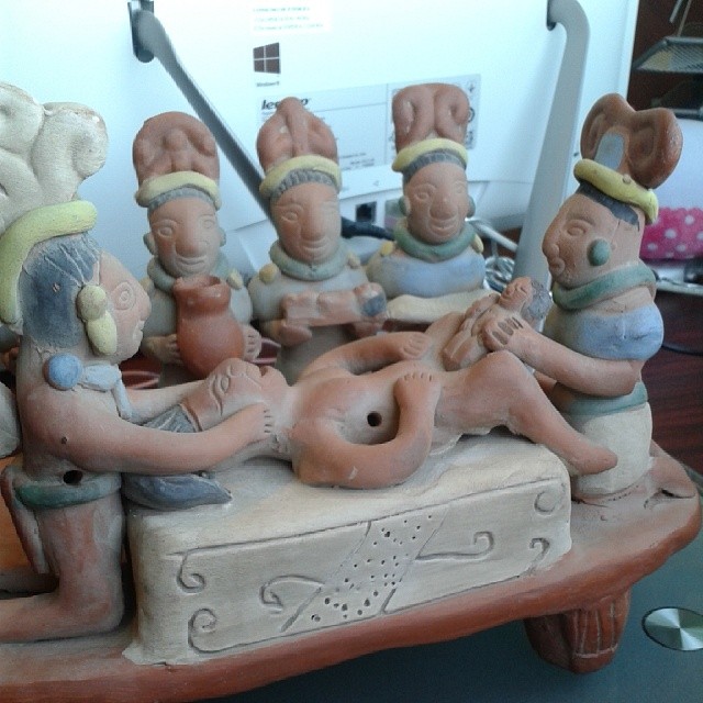 a ceramic group of various people sitting on top of a stone
