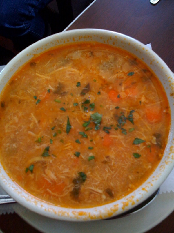 a bowl of soup with carrots, meat and parsley in it