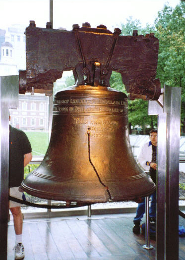 two people sit next to a large bronze bell
