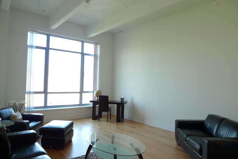 an empty living room with wooden floors and black sofas